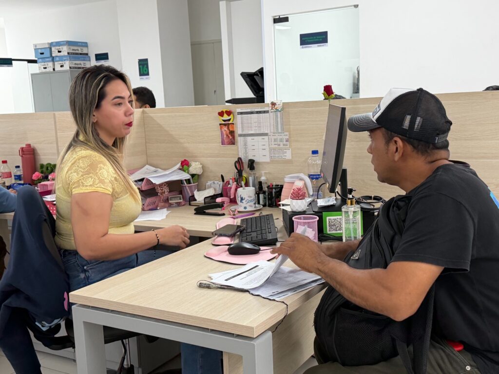 Patio de vehículos inmovilizados en Barranquilla junto a una pantalla que representa un trámite digital de tránsito.