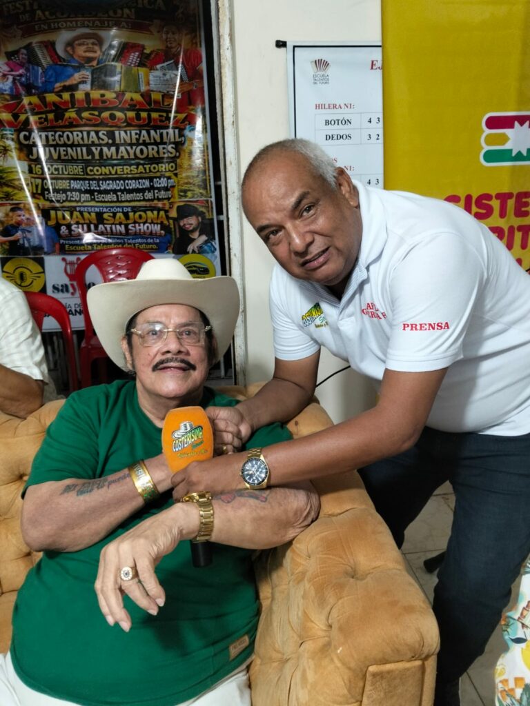 El músico Aníbal Velásquez con sombrero y camisa verde conversando junto al acordeonista Juan Sajona durante la presentación del clásico La Brujita.